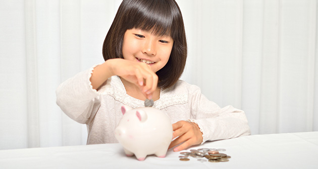 貯金箱にお金を入れる女の子